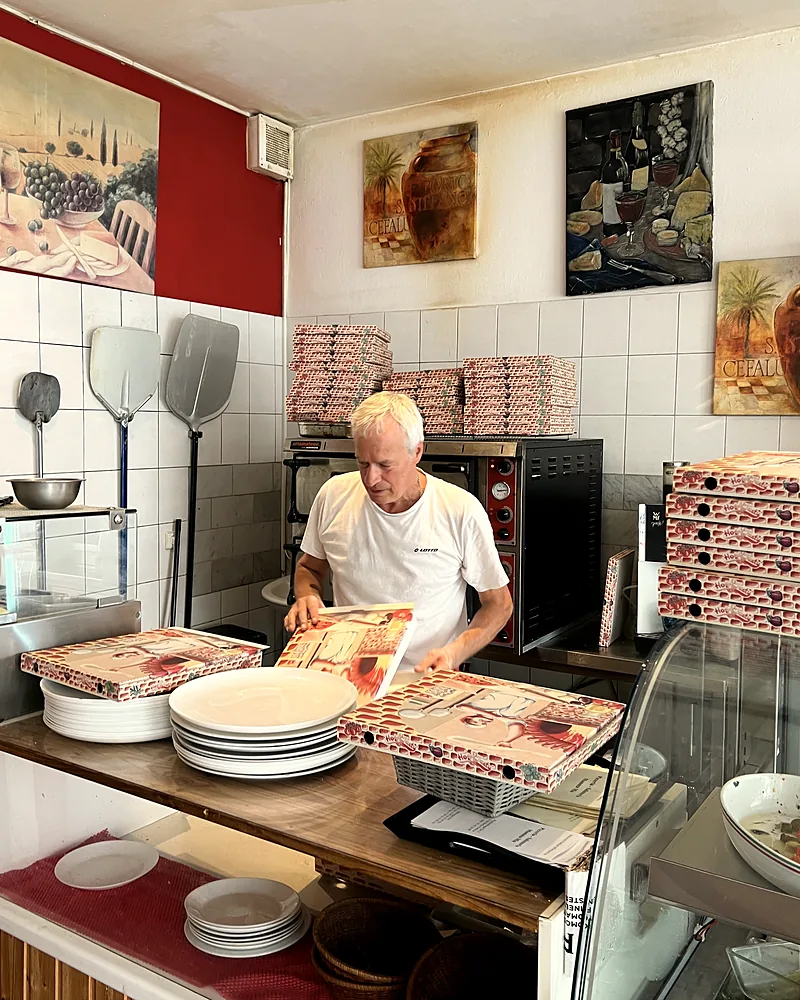 Antonino Volpe an der Theke, vor ihm gestapelte Pizzakartons und Teller